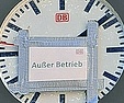 Eine Uhr mit DB-Logo, darauf ist mit Klebeband ein Schild "Außer Betrieb" befestigt, auf dem ebenfalls ein DB-Logo erkennbar ist.