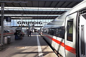 ICE steht am Bahnsteig. Im Hintergrund Abschluss der Bahnsteighalle mit Aufschrift 'Grundig'.