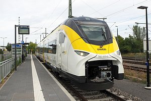 Zug der Baureihe 563 (Mireo Plus B) in wei&szlig;, gelb und schwarz, steht an einem Seitenbahnsteig. Auf dem Bahnsteig ist ein Zugzielanzeiger abweichend von den DB-Bauformen zu erkennen, und ein Warteh&auml;uschen.
