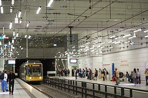 Unterirdische Stadtbahnstation Marktplatz (Kaiserstra&szlig;e). Ein Zug der Linie S2 nach Rheinstetten f&auml;hrt ein. Zahlreiche Menschen auf den beiden Seitenbahnsteigen. Im oberen Bereich Oberleitung und aufwendige Beleuchtung.