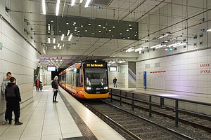 Unterirdische Stadtbahnstation Marktplatz (Pyramide). Ein Zug der Linie S1 nach Bad Herrenalb f&auml;hrt ein. Nur wenige Menschen auf den beiden Seitenbahnsteigen, das dritte Gleis ist nicht zu sehen. Im oberen Bereich Oberleitung und Beleuchtung.