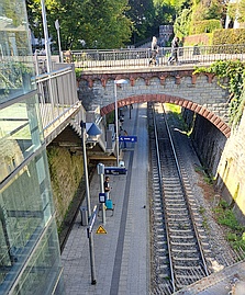 Blick von oben auf ein Gleis mit links liegendem Bahnsteig, darüber eine Br&uum;cke, im Hintergrund ein Teil eines Tunnelportals