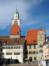 Blick auf einen historischen Gebäudekomplex mit zwei Türmen, dahinter ein noch höherer Kirchturm