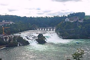 in Bildmitte der Rheinfall Schaffhausen, oberhalb ein Brücke, rechts ein Schloss