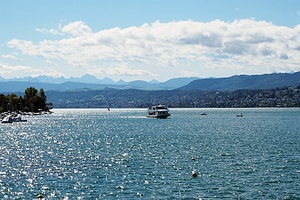 See mit kleinerem Passagierschiff, im Hintergrund hohe Berge