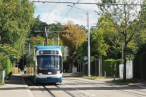 Straßenbahn in den Farben weiß, blau und schwarz auf einer abwärts führenden Straße