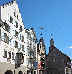 mehrstöckige historische Gebäude über die die Türme des Zürcher Großmünsters hinausragen